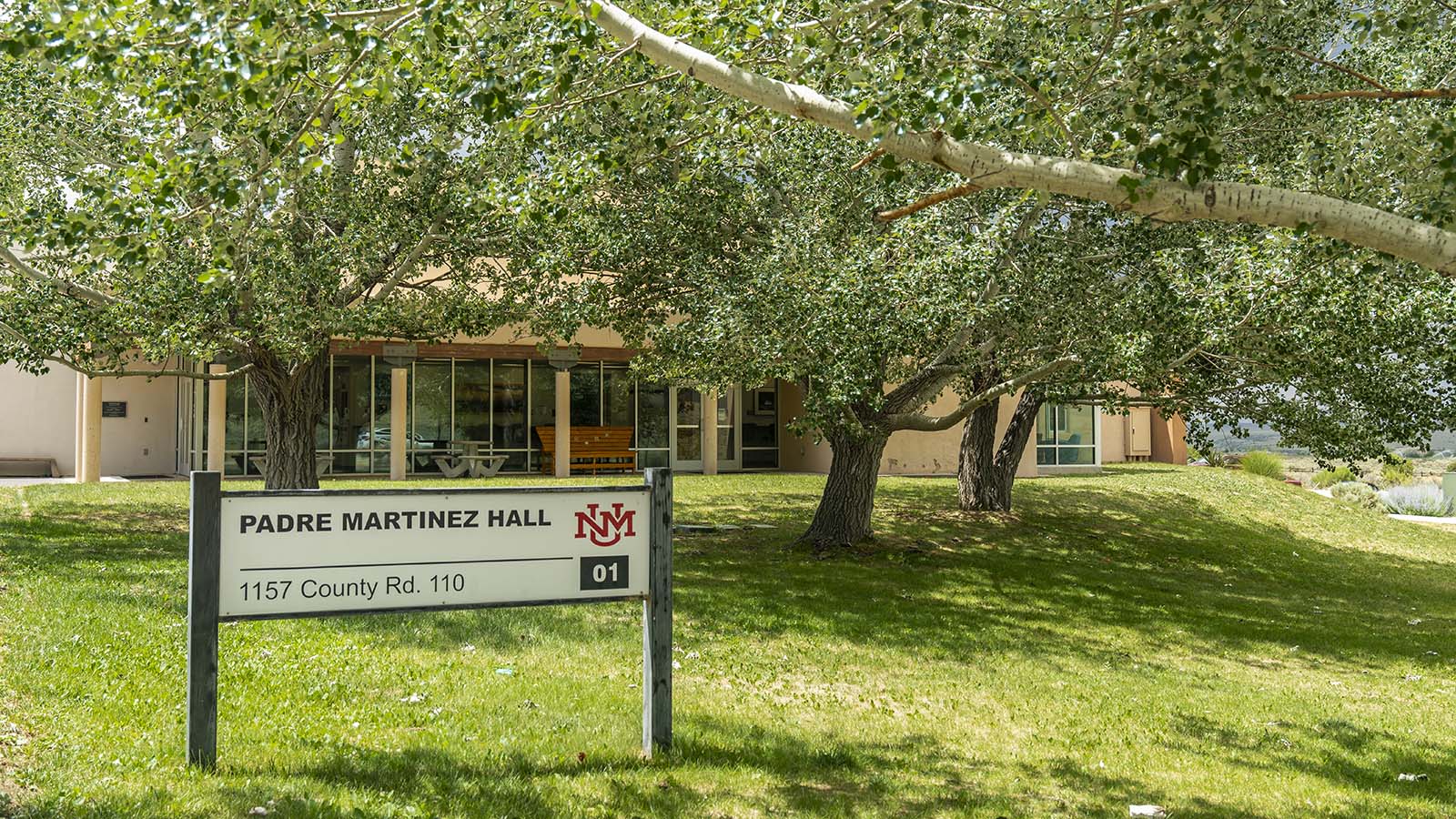 trees and grass outside of an adobe building on campus